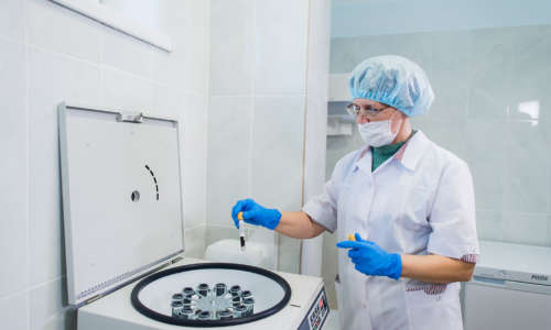 Closeup of a senior female chemist setting up some sample blood tubes inside a centrifuge for some test in a lab