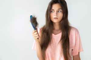 Woman Looking unhappily at hair brush- Hair Loss in Women at Hair Restoration Savannah