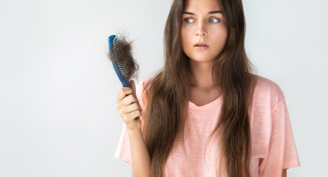 Woman Looking unhappily at hair brush- Hair Loss in Women at Hair Restoration Savannah
